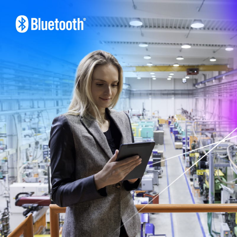 Woman on platform using tablet in modern industrial facility with Bluetooth technology for enhanced efficiency.
